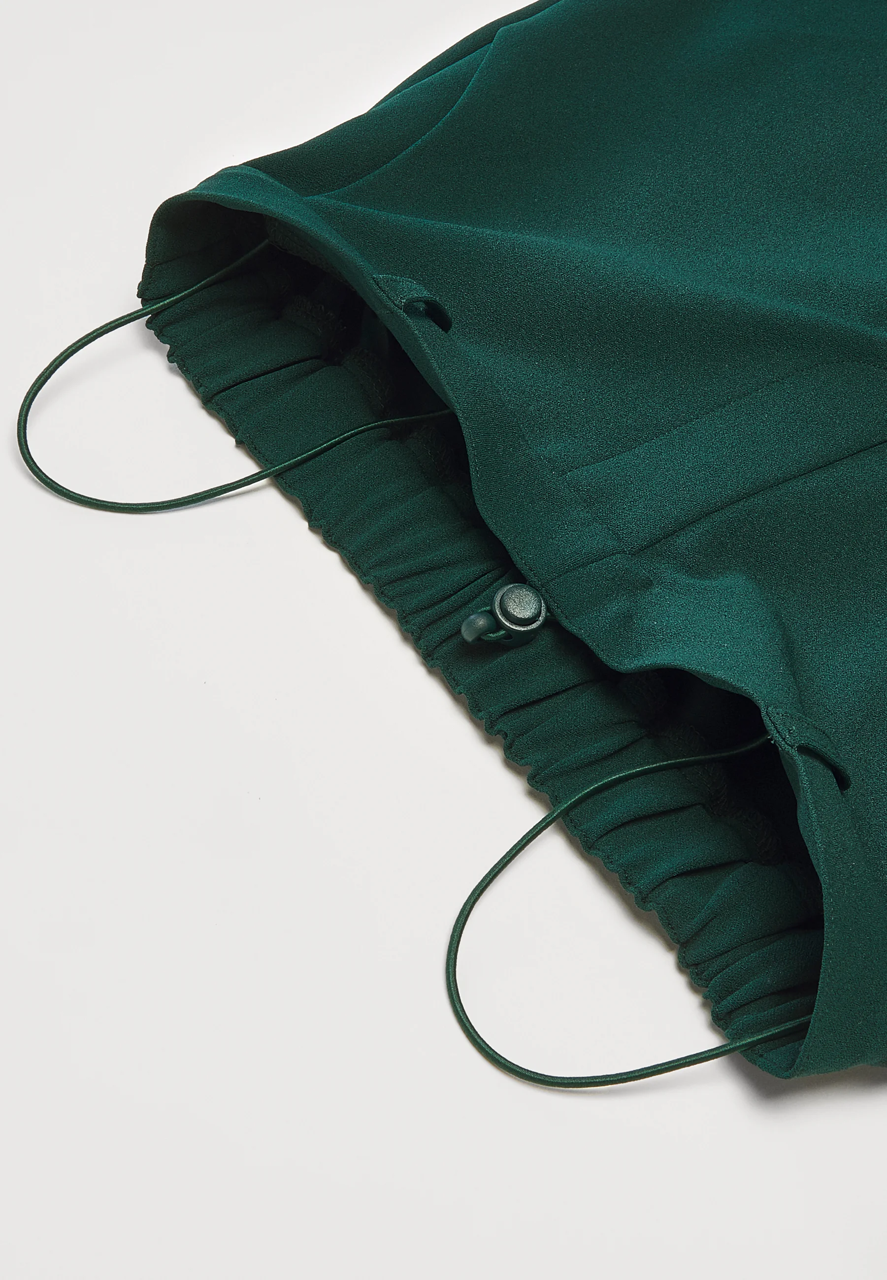 Dark green trousers shown with pulley ties to make them tighter
